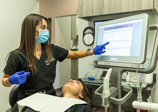 Denton dental team member touching computer monitor while treating dental patient