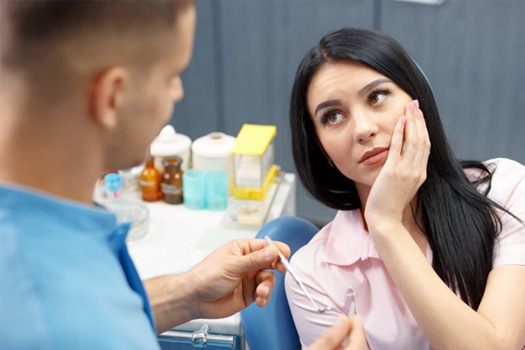 Patient in Shady Shores holding cheek in dentist chair